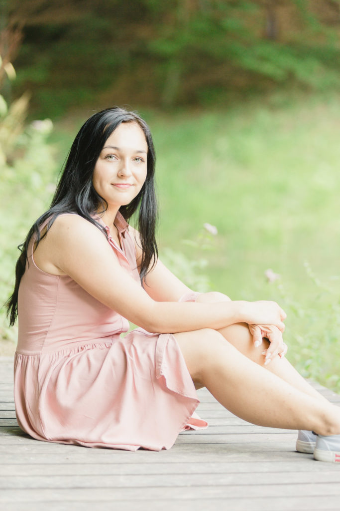 žena s dlhými čiernymi vlasmi v ružových šatách sedí na zemi