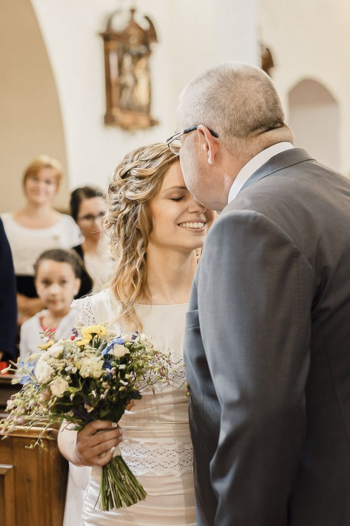 Svadobný otec dáva pusu neveste na čelo